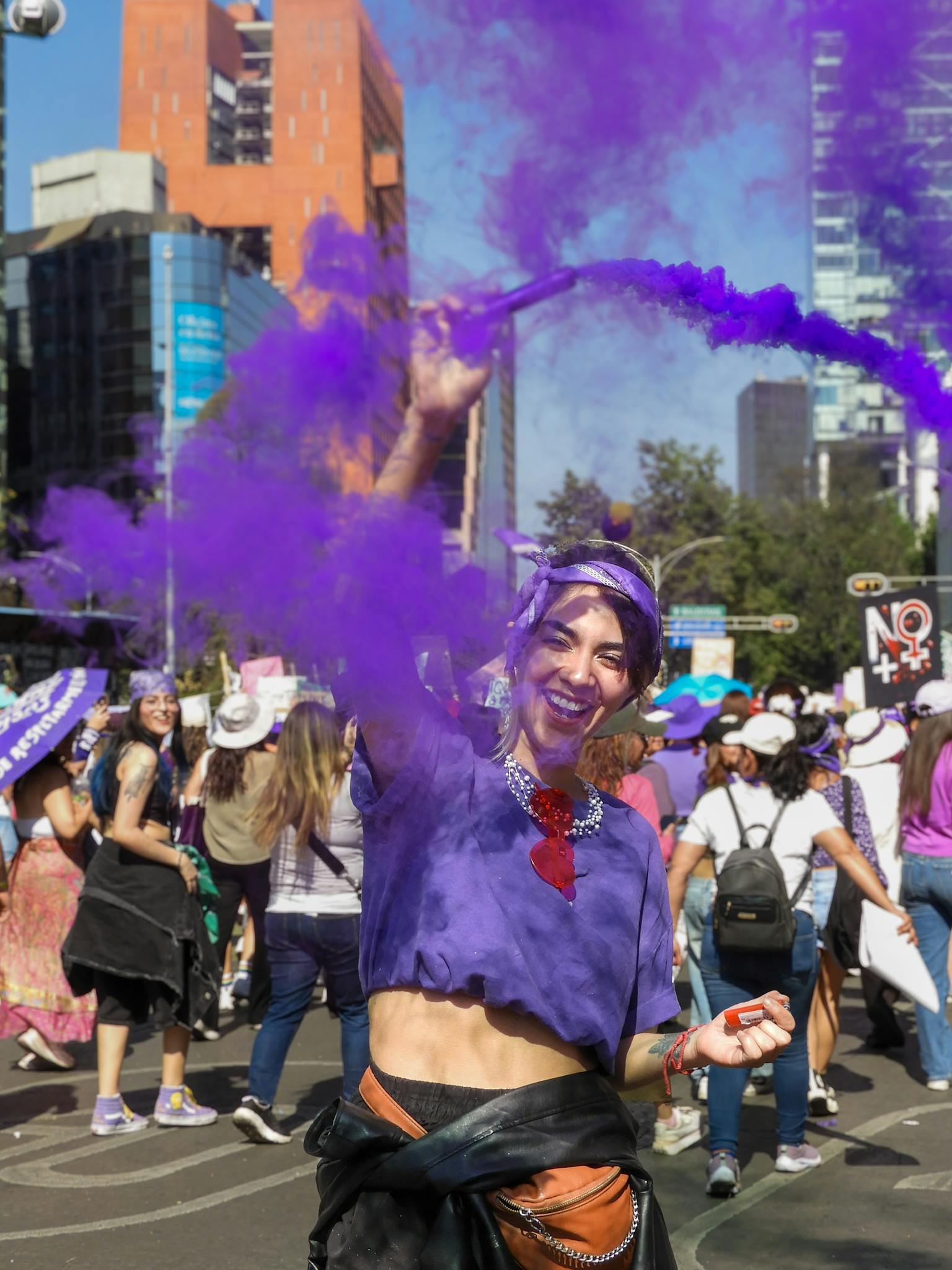 A vibrant public demonstration in Mexico City showcasing female empowerment with purple smoke.
